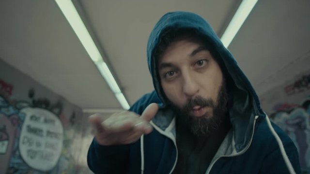 An eccentric controversial energetic  male urban rapper.Portrait and various performance shots of him performing in an underground city passage.