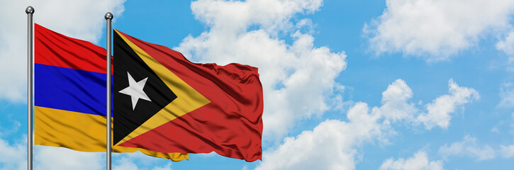 Naklejka premium Armenia and East Timor flag waving in the wind against white cloudy blue sky together. Diplomacy concept, international relations.