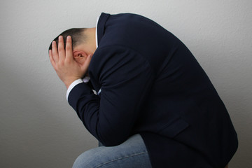 businessman sits with his head in his hands, symbol of problems, pain, illness, medical...