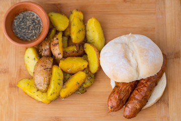 TYPICAL ARGENTINE SANDWICH CALLED CHORIPAN, SERVED WITH FRIED POTATOES AND CHIMICHURRI.