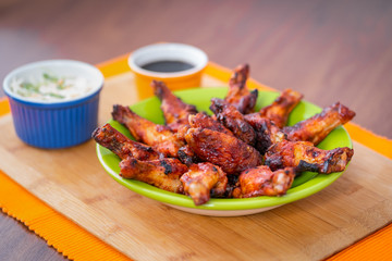 BBQ CHICKEN WINGS, SERVED WITH SALAD OF CABBAGE, IN GREEN PLATE AND YELLOW BACKGROUND
