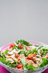 Salad with lettuce, tomato, mushrooms and fish. Pink tablecloth