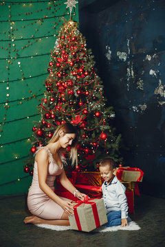 Beautiful mother in a white sweater. Family with cristmas gifts. Little boy near christmas tree