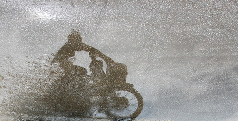 Shadow of the rider and motorcycle on the wet road, Ninh Binh, Vietnam.