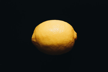 One ripe lemon on black background