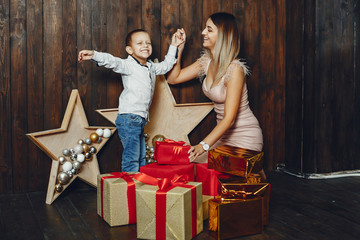 Beautiful mother in a white sweater. Family with cristmas gifts. Little boy in a white shirt