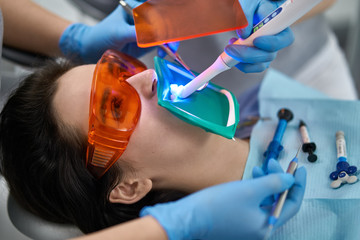 Pretty woman's teeth treatment in dental clinic