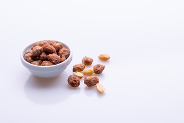 Peanuts praline sweet in a white bowl, on white background, soft light, copy space