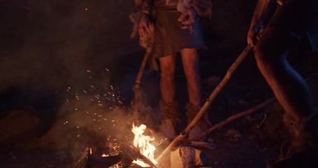 In dark two cavemen stand by the fire at night in a cave stone fun male ancient history stone age primeval evolution nature neanderthal homo sapiens bonfire man tribe campfire wild slow motion