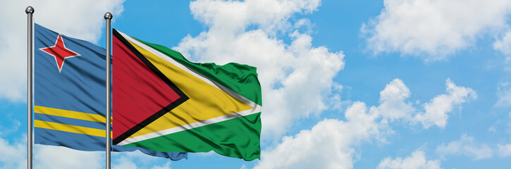 Aruba and Guyana flag waving in the wind against white cloudy blue sky together. Diplomacy concept, international relations.