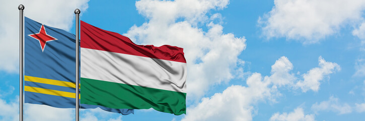 Aruba and Hungary flag waving in the wind against white cloudy blue sky together. Diplomacy concept, international relations.