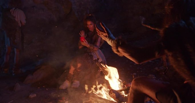 Funny tribe cavemen neanderthals wearing animal skin use phone sitting by the fire in a cave stone fun male ancient history evolution nature homo sapiens primitive campfire slow motion