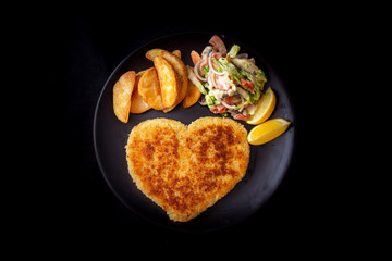 Heart shape Chicken Schnitzel with salad, fried potato wedges