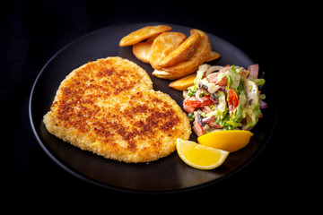 Heart shape Chicken Schnitzel with salad, fried potato wedges