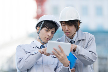 ヘルメットのビジネスマン　タブレットを確認