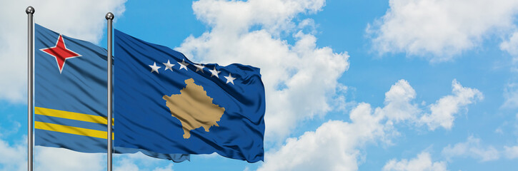 Aruba and Kosovo flag waving in the wind against white cloudy blue sky together. Diplomacy concept, international relations.
