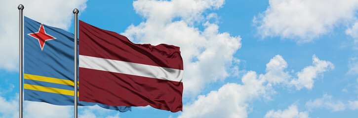 Aruba and Latvia flag waving in the wind against white cloudy blue sky together. Diplomacy concept, international relations.