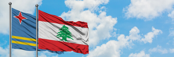 Aruba and Lebanon flag waving in the wind against white cloudy blue sky together. Diplomacy concept, international relations.