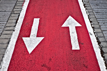 Up and down white dirrection arrows on neon red surface of a city biking lane.