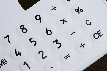 Closed up of white calculator buttons such as numbers, plus, minus, multiply and divind on black leather using as budget, loan, maths, investment banking and accounting