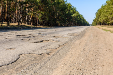 Big potholes on the damaged asphalt road