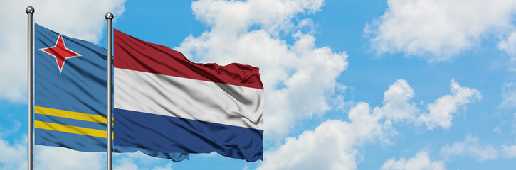 Aruba and Netherlands flag waving in the wind against white cloudy blue sky together. Diplomacy concept, international relations.