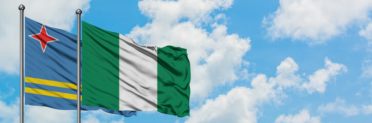 Obraz premium Aruba and Nigeria flag waving in the wind against white cloudy blue sky together. Diplomacy concept, international relations.