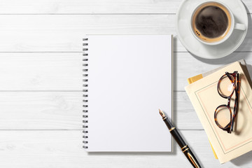 空白のノート、コーヒー、本、万年筆のある白木のテーブル