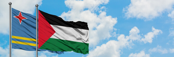 Obraz premium Aruba and Palestine flag waving in the wind against white cloudy blue sky together. Diplomacy concept, international relations.