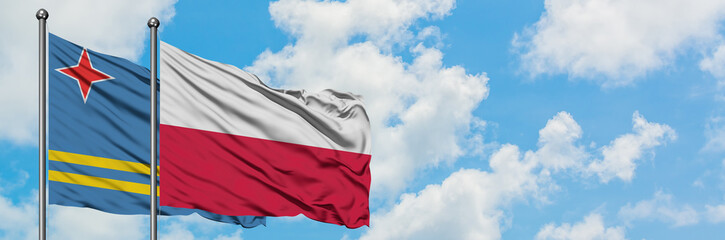 Fototapeta na wymiar Aruba and Poland flag waving in the wind against white cloudy blue sky together. Diplomacy concept, international relations.