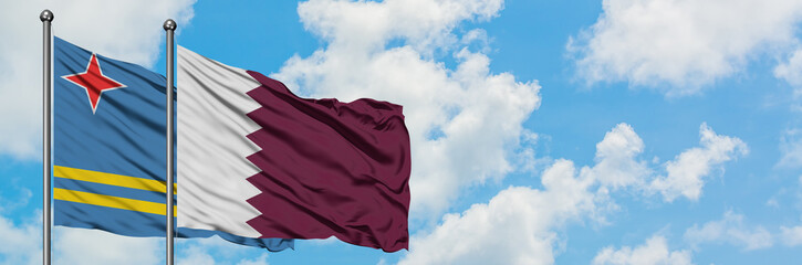 Aruba and Qatar flag waving in the wind against white cloudy blue sky together. Diplomacy concept, international relations.