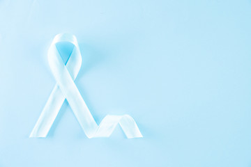 Blue ribbon on bright blue pastel background representing an annual event during the month of November to raise awareness of men's health issues and prostate cancer with copy space.