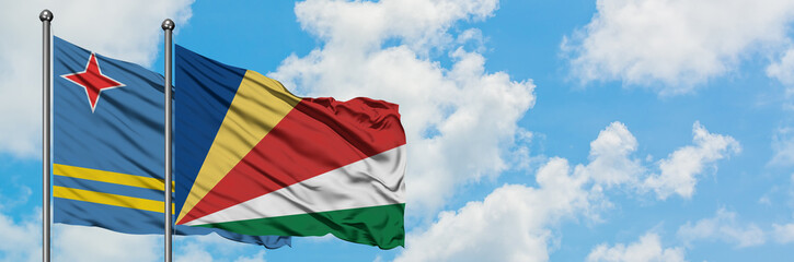 Aruba and Seychelles flag waving in the wind against white cloudy blue sky together. Diplomacy concept, international relations.