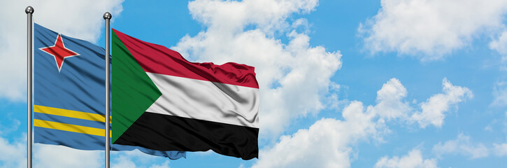 Fototapeta na wymiar Aruba and Sudan flag waving in the wind against white cloudy blue sky together. Diplomacy concept, international relations.