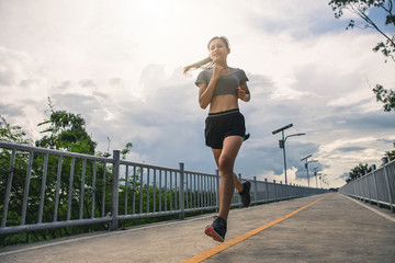 Fototapeta na wymiar Young woman running in the nature. Healthy lifestyle and sport concepts. Runner training in a urban area.The woman with runner on the street be running for exercise.