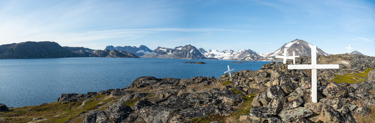 A panoramic view of a cemetery in Greenland, with a gorgeous glacier on the opposite side of the ocean.  © Max