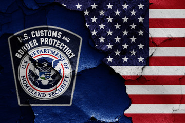flags of U.S. Customs and Border Protection and USA painted on cracked wall