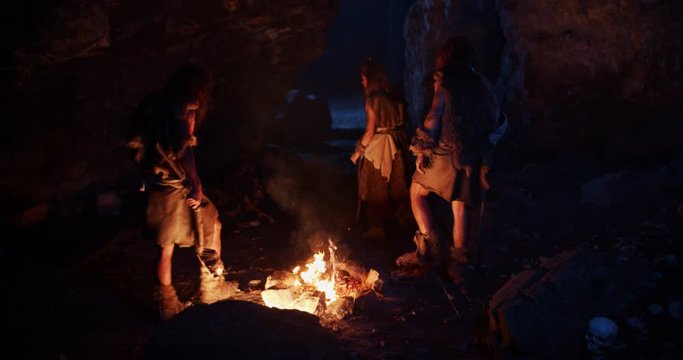 Wild cavemen neanderthals wearing animal skin get out of the cave at dark night near fire stone fun ancient history portrait evolution homo sapiens primitive campfire slow motion
