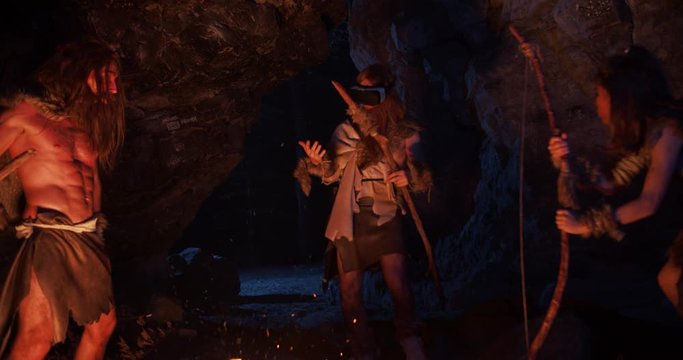 Near fire cavemen holding weapon neanderthals wearing animal skin stand beating screaming breasts use virtual reality glasses in prehistoric forest at night evolution stone cave slow motion