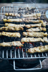 Pork satay grilling on stove.