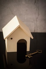 Home owning concept. Wooden house and key on a black background