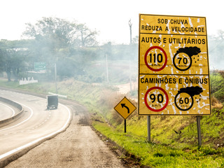 Signpost indicating speed limit on dry and wet roads on Comandante João Ribeiro de Barros Highway, SP 294, near the entrance of Jafa district, in Garca municipality - obrazy, fototapety, plakaty