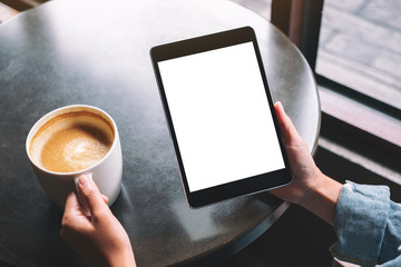 Mockup image of a woman holding black tablet with white blank desktop screen while drinking coffee