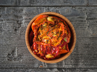 Dried tomatoes in a wooden bowl in the middle of a wooden table. Vegetarian food. Flat lay.