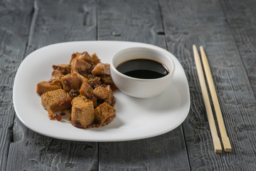 Soy sauce with grilled tofu cheese on a white plate and chopsticks.