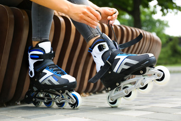 Woman wearing modern inline roller skates in city park, closeup