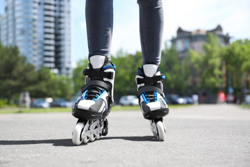Woman with modern inline roller skates in city park, closeup