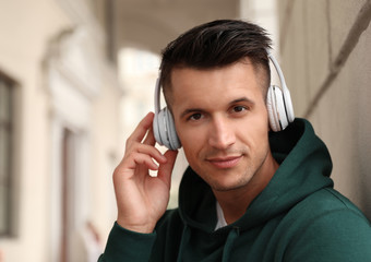 Portrait of handsome young man with headphones listening to music outdoors