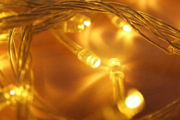 Glowing Christmas lights on color background, closeup view