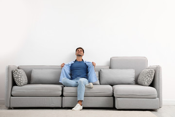 Obraz premium Young man relaxing on sofa against white wall